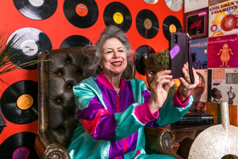 elderly woman in purple and pink jacket taking a selfie