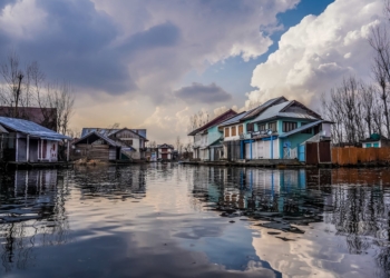 blue and white wooden houses beside river under blue and white cloudy sky