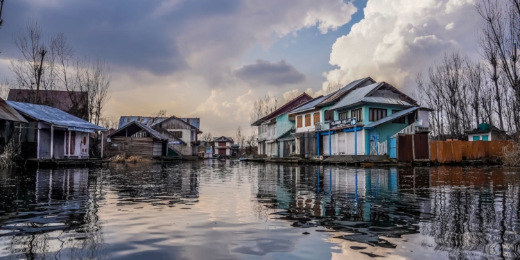 blue and white wooden houses beside river under blue and white cloudy sky