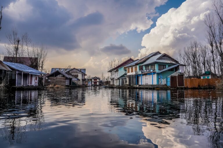 blue and white wooden houses beside river under blue and white cloudy sky
