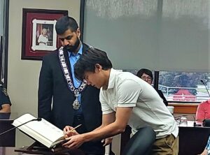 Picture of Maxwell Hum signing the Book of Recognition