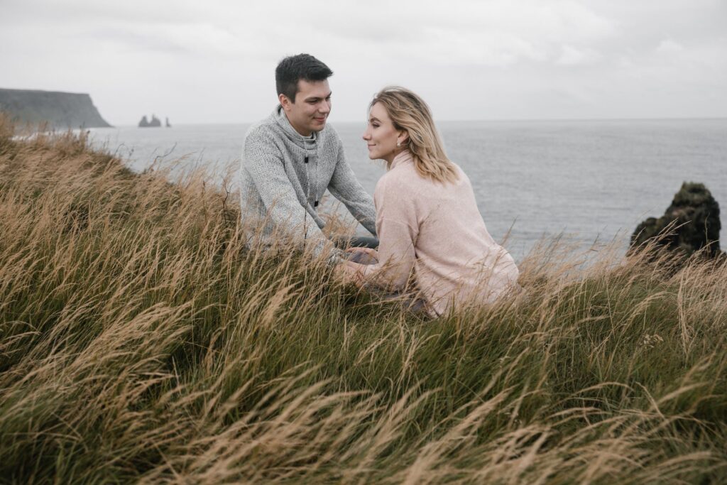 cheerful couple holding hands while spending time on seashore