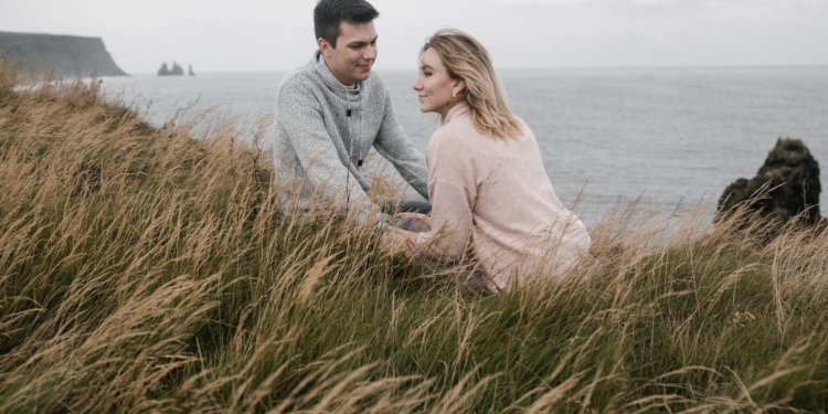 cheerful couple holding hands while spending time on seashore