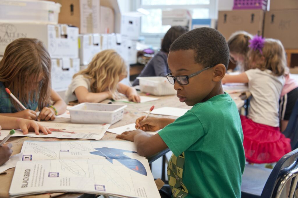 A child looking at a book and writing