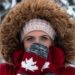 woman wearing red-and-brown parka coat and gray-and-red Canada knit mittens