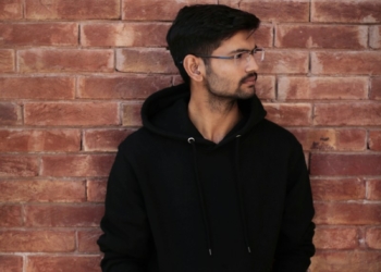 a man standing in front of a brick wall