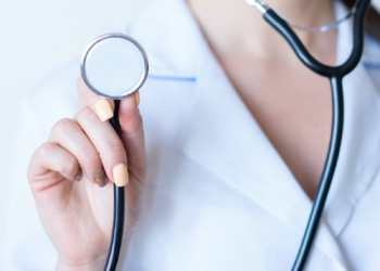 a woman in a white shirt holding a stethoscope