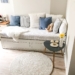 blue and white pillows on white couch and round white area mat on floor