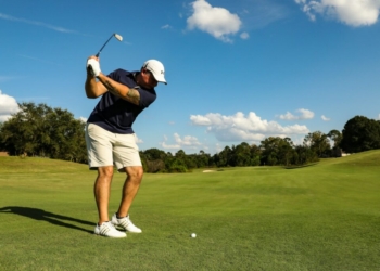 man in black shirt and white shorts playing golf during daytime