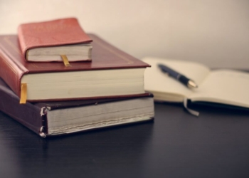 selective focus photography of three books beside opened notebook