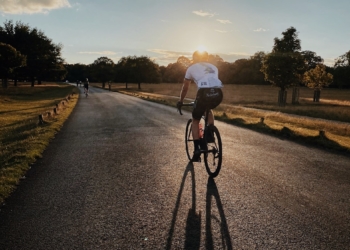 man in white shirt riding bicycle on gray asphalt road during daytime