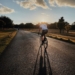 man in white shirt riding bicycle on gray asphalt road during daytime