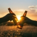 photography of person holding glass bottles during sunset