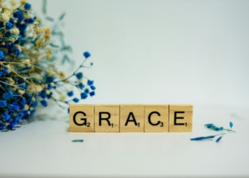 a wooden block that says grace next to a bouquet of flowers