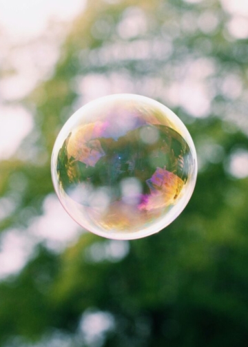 a close up of a soap bubble with trees in the background