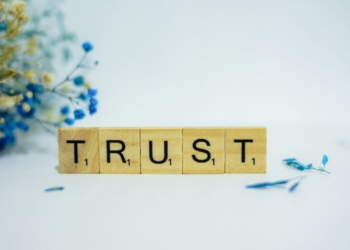 a wooden block that says trust, surrounded by blue flowers