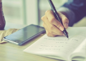 a person writing on a piece of paper with a pen