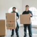 Two Men Standing Carrying Cardboard Boxes