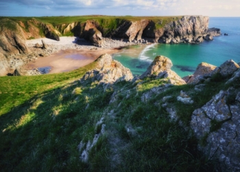 rocky hill with grass facing ocean