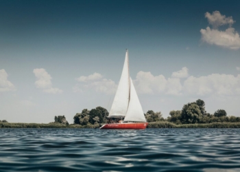 red sail boat on body of water during daytime