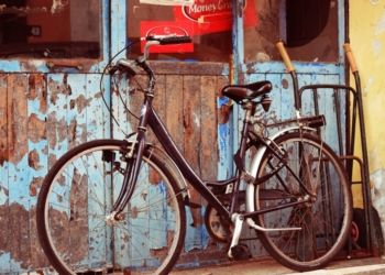 black and gray cruiser bicycle in front of blue wooden door