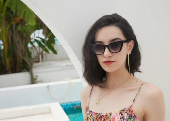 A woman wearing sunglasses standing next to a pool