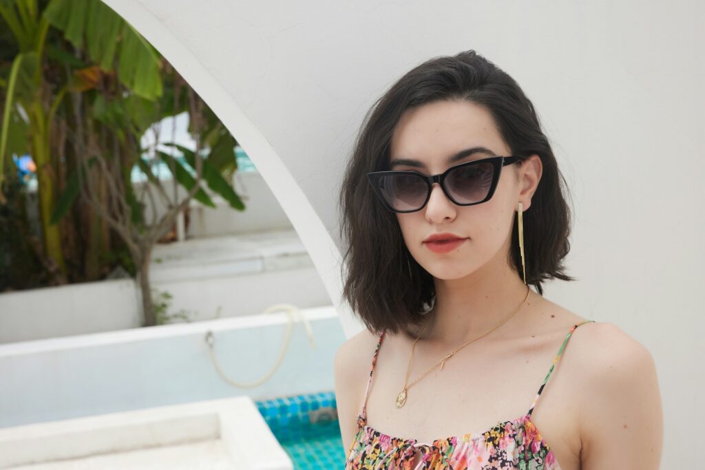 A woman wearing sunglasses standing next to a pool