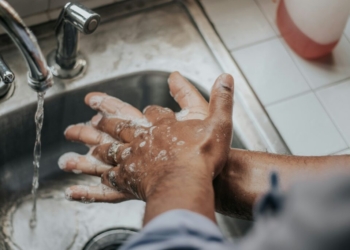 person in white shirt washing hands