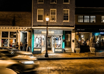 three people standing on roadside near building during nighttime