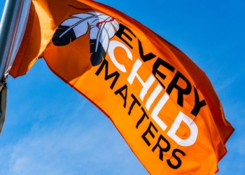 a very large orange flag flying in the sky