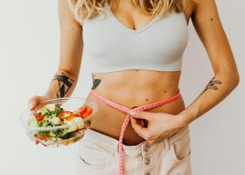 Woman in Sports Bra Holding a Measuring Tape and Bowl of Salad