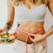 Woman in Sports Bra Holding a Measuring Tape and Bowl of Salad