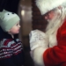 toddler in black sweater standing in front of Santa Claus