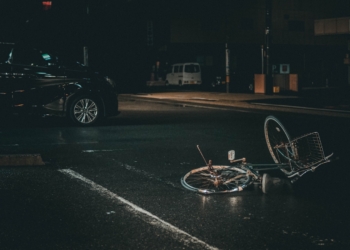 grey bicycle on road near black vehicle at nighttime