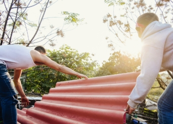 woman in white tank top and white pants standing beside red curtain during daytime