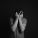 A grayscale portrait of a man covering his face, depicting emotion and mental health themes.