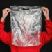 Person Wearing Red Top Holding Clear Plastic Bag