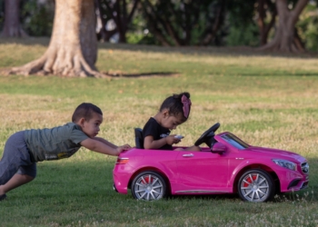 two children playing with a pink toy car