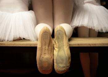 a pair of ballet shoes sitting on top of a wooden shelf