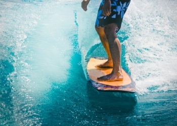 man riding wave with orange surfboard