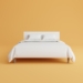 a bed with a white cover and pillows on top of it