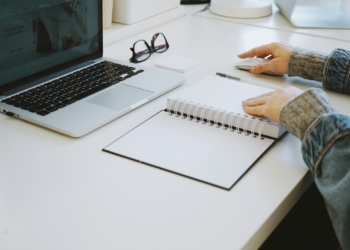 person touching white spiral notebook
