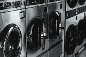 Black and white image of industrial washing machines in a retro style laundry facility.