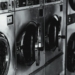 Black and white image of industrial washing machines in a retro style laundry facility.