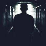 Silhouette of a person standing in a shadowy tunnel, evoking mystery.