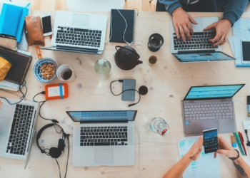 people sitting down near table with assorted laptop computers