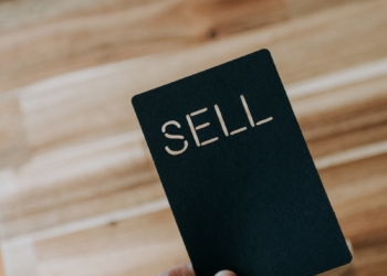 a person holding a black book with the word sell written on it