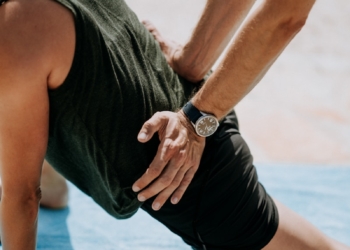 person pressing man back kneeling on blue towel