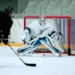 man taking aim for goal on hockey goalie