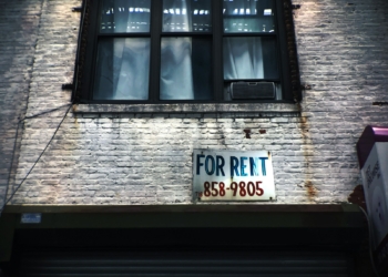 for rent sign on wall below window glass of building